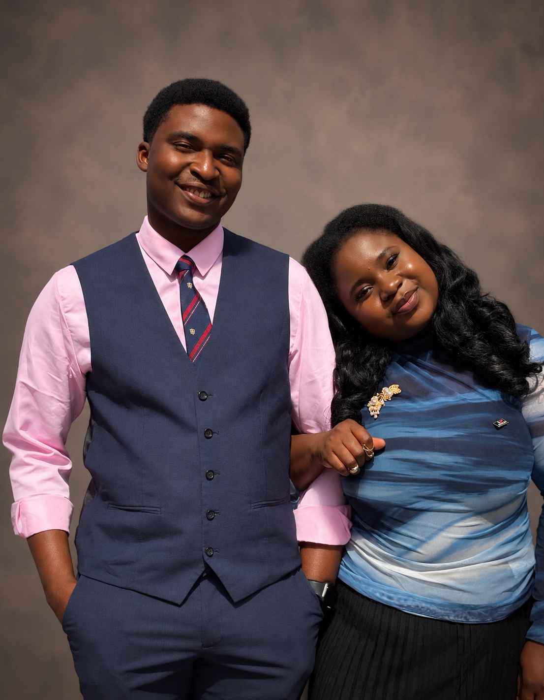 A smiling couple photographed together against a warm studio backdrop